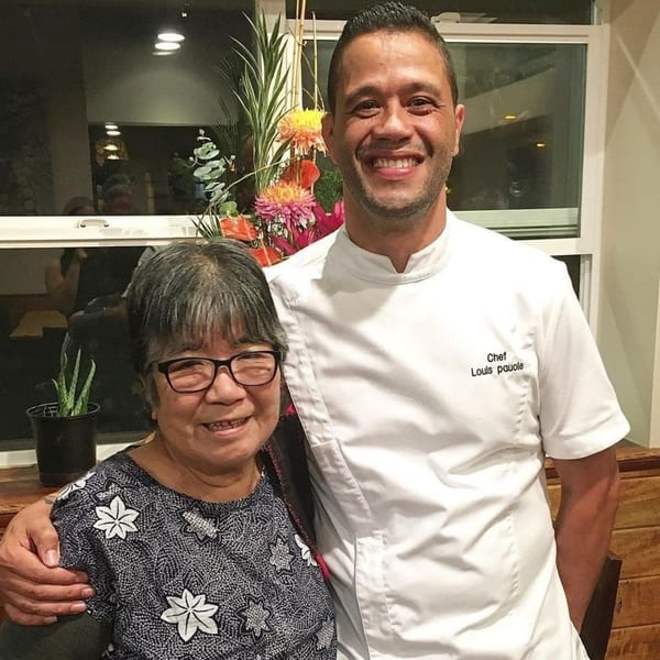 Chef Louis Pauole of Miyo's Restaurant smiling with a woman, with flowers in the background.